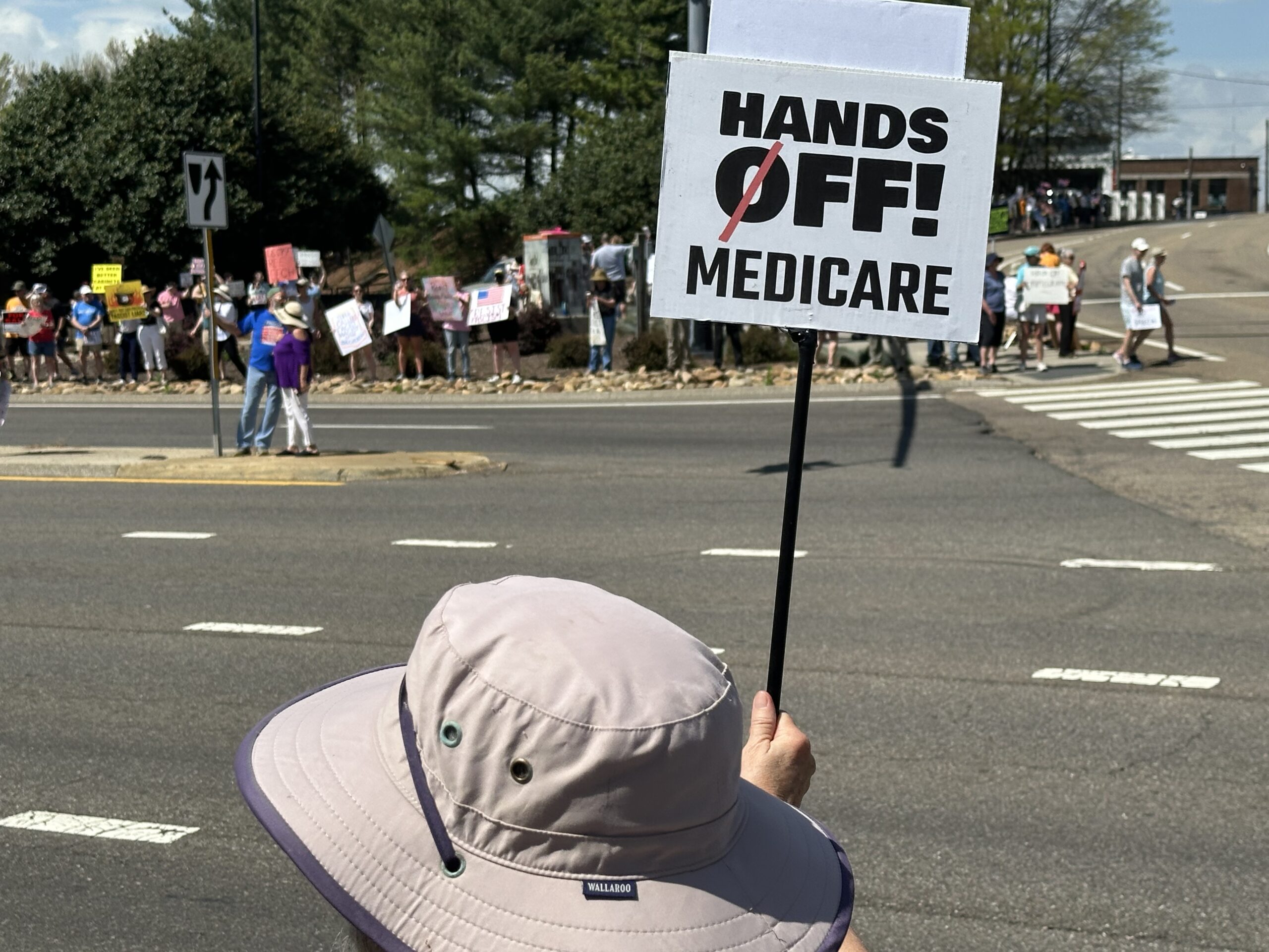 Protesters at a "Hands Off" rally in Knoxville, Tenn., on April 5, 2025. In the foreground, someone holds a sign saying "Hands Off! Medicare"